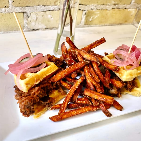 Chicken and waffles sliders with pickled onions and a side of sweet potato fries.