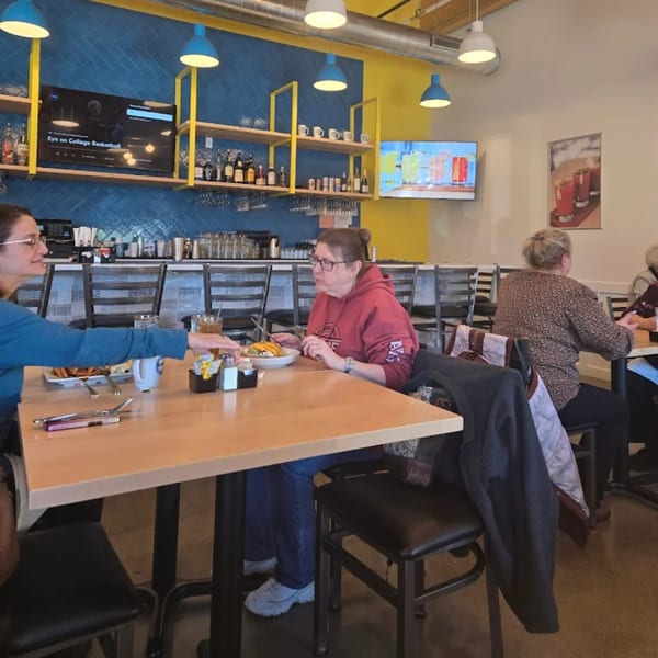 Diners enjoying brunch at tables in a brightly lit restaurant with blue and yellow walls.