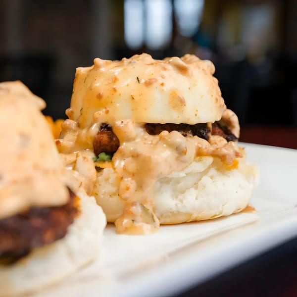 Close-up of a brunch biscuit sandwich with a thick, creamy sauce and meat filling.